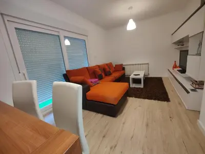 a living room with an orange couch and a table at Ático espacioso en zona céntrica in Sarria