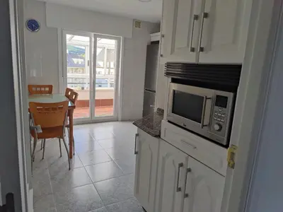 a kitchen with a microwave and a table with chairs at Ático espacioso en zona céntrica in Sarria
