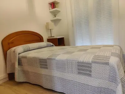 a bedroom with a bed with a blue and white blanket at Ático espacioso en zona céntrica in Sarria