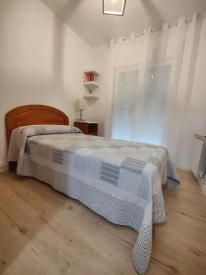 a white bedroom with a bed and a window at Ático espacioso en zona céntrica in Sarria