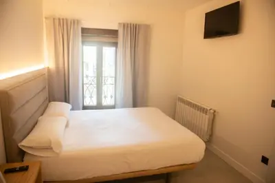 a bedroom with a white bed and a window at pension campillo in Fonsagrada