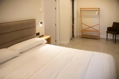 a bedroom with a bed and a chair and a mirror at pension campillo in Fonsagrada