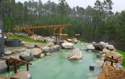 a river with rocks and a wooden bridge at Apartamento 16 in Ribadavia