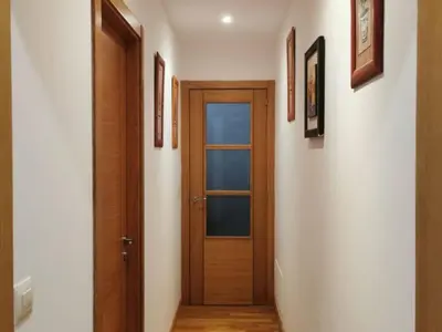 a hallway with a wooden door and pictures on the wall at Apartamento con 2 habitaciones y vistas a la Ría del Burgo in Cambre