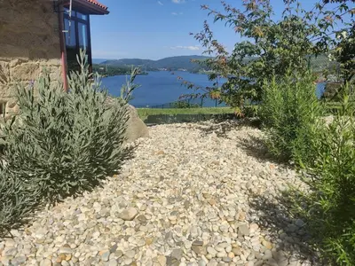 a gravel path with bushes and a view of a lake at Casa da Ramona in Ribadavia