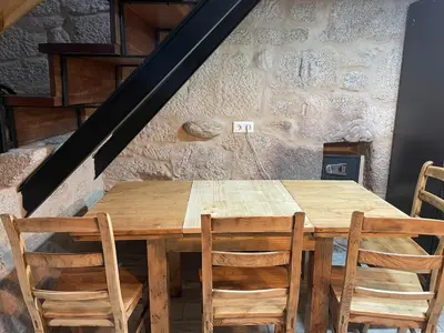a wooden table with four chairs and a staircase at A casiña do abuelo Pepe in A Lama