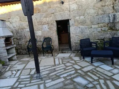 a group of chairs sitting in front of a stone building at A casiña do abuelo Pepe in A Lama