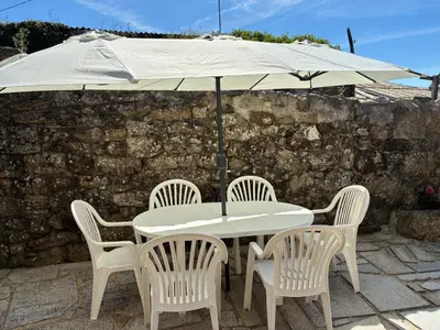 a white table with chairs and an umbrella at A casiña do abuelo Pepe in A Lama