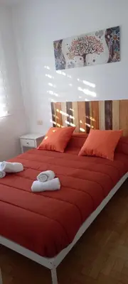 a large bed with red sheets and orange pillows at Vila Montecelos in Antas de Ulla