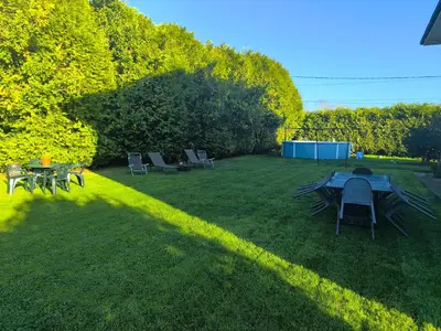 a backyard with a table and chairs on the grass at Gran chalet con jardín, piscina y BBQ in Sada