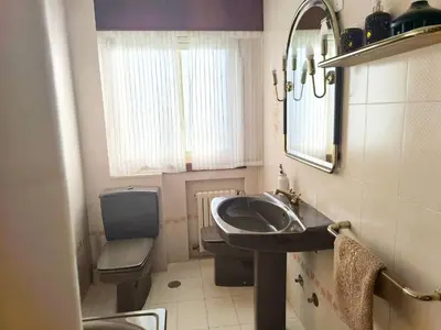 a bathroom with a sink and a toilet and a mirror at Gran chalet con jardín, piscina y BBQ in Sada