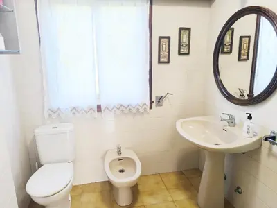 a white bathroom with a toilet and a sink at Gran chalet con jardín, piscina y BBQ in Sada