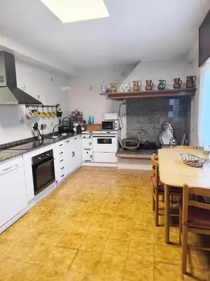 a kitchen with white cabinets and a wooden floor at Gran chalet con jardín, piscina y BBQ in Sada