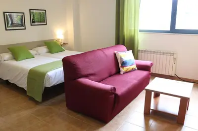 a bedroom with a bed and a purple couch at Apartamentos Turísticos Cancelas by Bossh Hotels in Santiago de Compostela