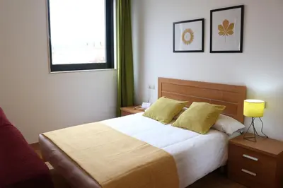 a bedroom with a bed with yellow pillows and a window at Apartamentos Turísticos Cancelas by Bossh Hotels in Santiago de Compostela