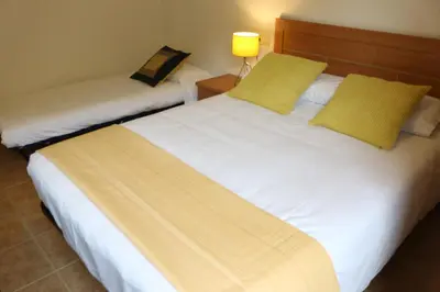 two beds in a hotel room with yellow pillows at Apartamentos Turísticos Cancelas by Bossh Hotels in Santiago de Compostela