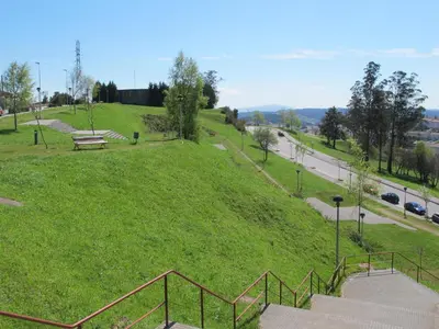 a grassy hill with a park with a bench on it at Apartamentos Turísticos Cancelas by Bossh Hotels in Santiago de Compostela