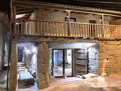 a large stone building with a wooden staircase in it at O Luar in Piñeira Seca