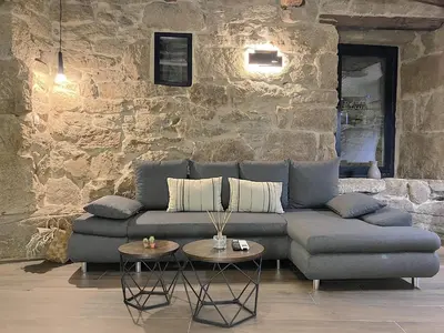 a living room with a couch and a stone wall at O Luar in Piñeira Seca
