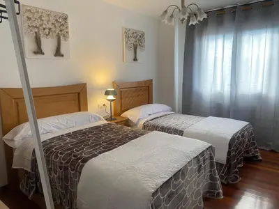a bedroom with two beds and a window at Alojamiento Camiña in Caldas de Reis