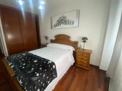 a bedroom with a bed and a wooden dresser with a bedspread at Alojamiento Camiña in Caldas de Reis