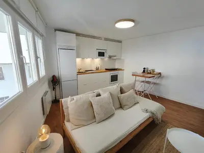 a living room with a white couch and a kitchen at White & Wood Miño Apartament in Miño