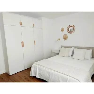 a white bedroom with a bed and white cabinets at White & Wood Miño Apartament in Miño