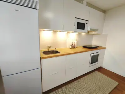 a kitchen with white cabinets and a sink at White & Wood Miño Apartament in Miño