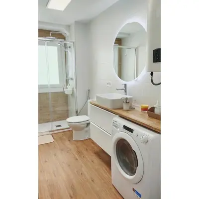 a bathroom with a washing machine and a toilet at White & Wood Miño Apartament in Miño