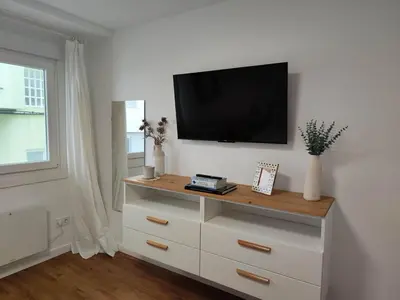 a white dresser with a flat screen tv on a wall at White & Wood Miño Apartament in Miño