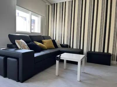 a living room with a black couch and a white table at Dream House II -Termas cerca -parking gratis- in Ourense