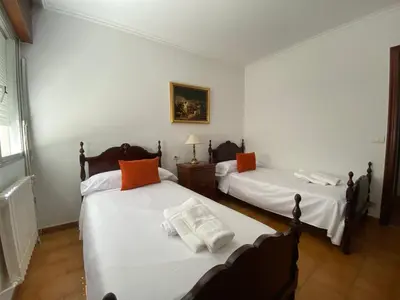 a bedroom with two beds with white sheets and orange pillows at Royal Street Refuge in Caldas de Reis