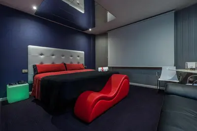 a bedroom with a large bed with a red chair at Motel Venus La Coruña in Guísamo