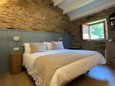 a bedroom with a large bed in a stone wall at Luar do Sarela Rooms in Santiago de Compostela