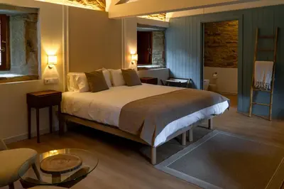 a bedroom with a large bed and a table at Luar do Sarela Rooms in Santiago de Compostela