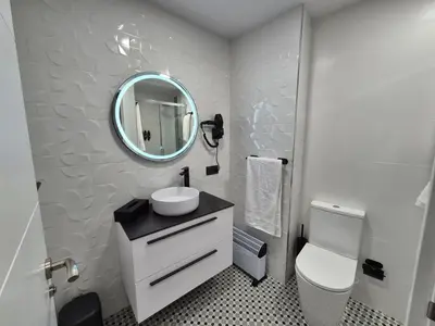 a white bathroom with a sink and a mirror at Máximo Meridio in Ourense