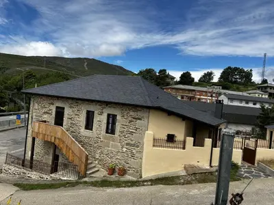 a small stone building with a black roof at El tejo milenario in Requejo