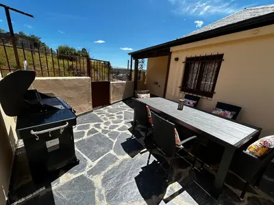 a patio with a grill and a table and chairs at El tejo milenario in Requejo