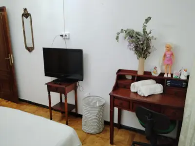 a bedroom with a desk with a tv and a table with a chair at Casa albergue Pty in Sarria