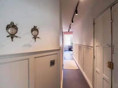a hallway with white walls and wooden floors and two clocks on the wall at La Fantástica Pontedeume 1 in Puentedeume