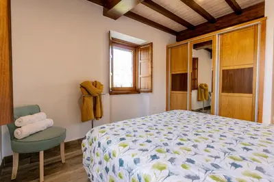 a bedroom with a bed and a chair and a window at Lagar de Beuvas in Camanzo