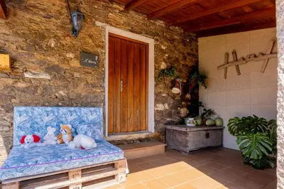 two stuffed animals sitting on a bench in front of a door at Lagar de Beuvas in Camanzo