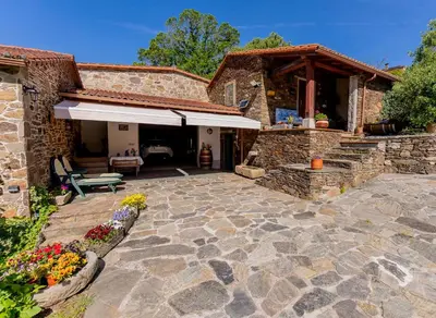 a stone house with a patio with a table at Lagar de Beuvas in Camanzo