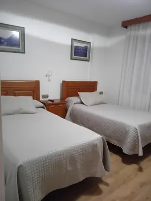 two beds in a hotel room with white sheets at El Ancla in Ponferrada
