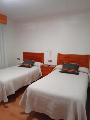 two beds in a room with white walls at El Ancla in Ponferrada