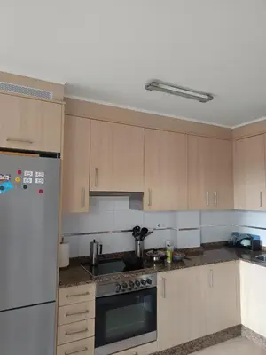 a kitchen with white appliances and wooden cabinets at Foz te espera in Foz