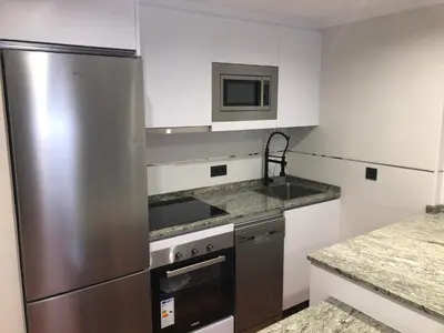 a kitchen with a stainless steel refrigerator and a sink at Aparthotel A&M VIÑA II in Jove