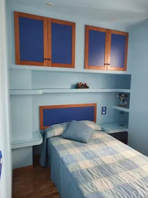a bedroom with a bed with blue walls and wooden cabinets at Apartamento vacacional Meira in Meira