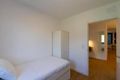 a white bedroom with a bed and a hallway at Urbanfive apartamentos Ourense centro in Ourense