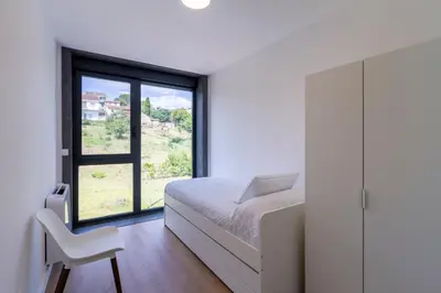 a bedroom with a bed and a chair and a window at Urbanfive apartamentos Ourense centro in Ourense